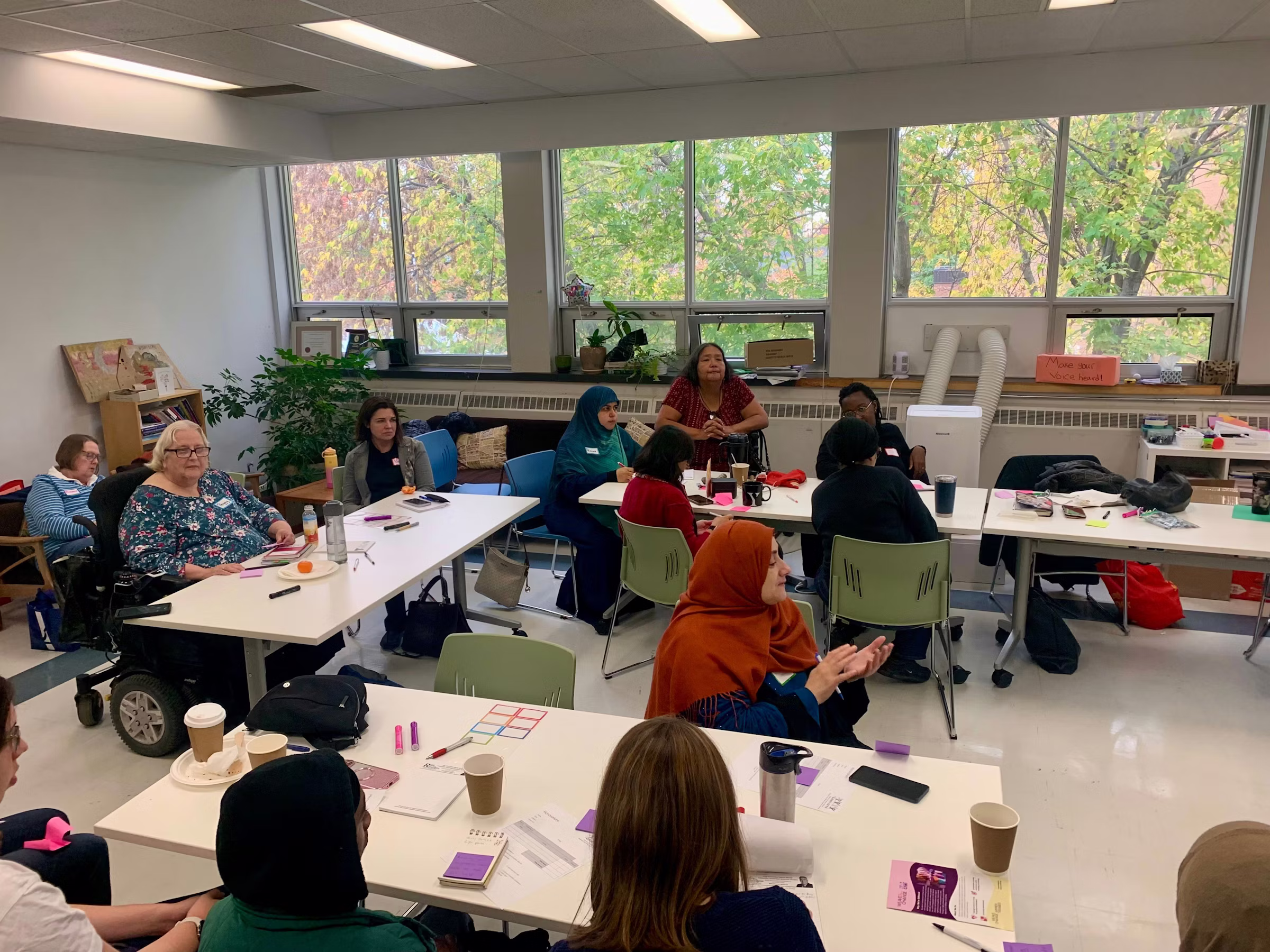 Group of women in a room around a semi cirlce of tables participating in a training